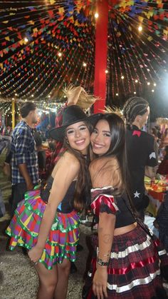 two young women are posing for the camera at an outdoor event with lights and streamers in the background