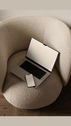 an open laptop computer sitting on top of a chair next to a mouse and cell phone