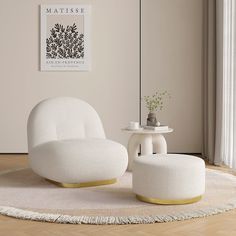 a white chair and ottoman sitting on top of a wooden floor next to a table