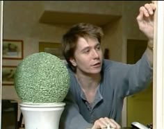 a woman sitting at a table in front of a large green ball on top of a desk