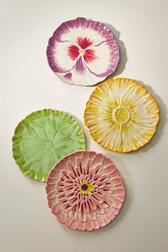 three plates with different designs on them sitting next to each other in the shape of flower petals