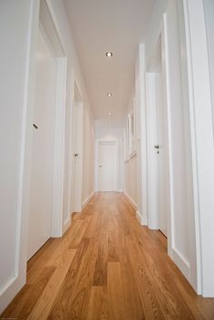 an empty hallway with white walls and wooden floors