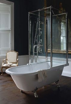 an old fashioned claw foot bathtub in a dark room with a painting on the wall