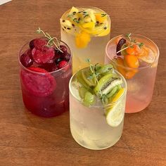 three glasses filled with different types of drinks on top of a wooden table next to each other