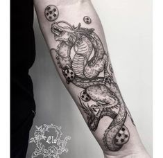 a black and white photo of a dragon tattoo on the right forearm, with balls coming out of it