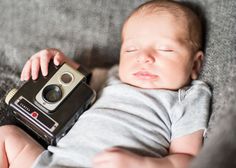 a baby laying on top of a couch with a camera next to it's face