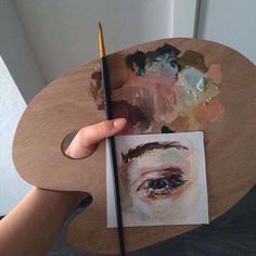 a person holding a paintbrush over a piece of paper with a painting on it