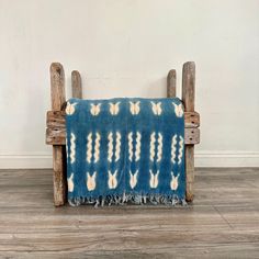 a blue and white blanket sitting on top of a wooden bench next to a wall