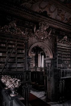 an old library with many bookshelves and flowers in vases on the floor