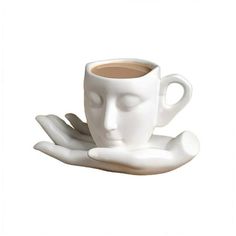 a white coffee cup sitting on top of a saucer with its eyes closed and hands extended