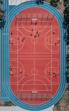 an overhead view of a basketball court with people playing on it and trees in the background