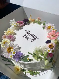 a birthday cake decorated with flowers in a box