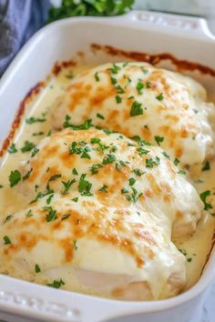 a casserole dish with chicken covered in cheese and garnished with parsley