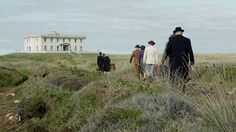 four people are walking up a hill towards a house