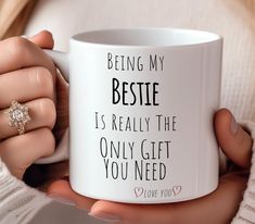 a woman holding a coffee mug with the words being my bestie is really the only gift you need