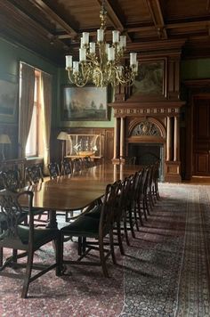 a large dining room table and chairs in front of a fire place with a chandelier hanging from the ceiling