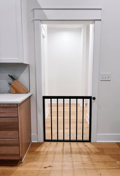 an open door leading to a kitchen with wooden floors and white walls in the background