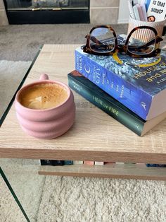 a cup of coffee sitting on top of a table next to books and eyeglasses