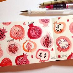 an open notebook with pomegranates on it and a pen next to it