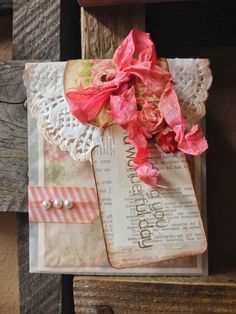 a close up of a piece of paper on a wooden surface with lace and flowers