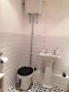 a white toilet sitting next to a black and white sink in a bathroom under a faucet