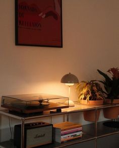 a record player sitting on top of a table next to a lamp and potted plant