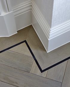 the corner of an empty room with white walls and wood flooring on the ground