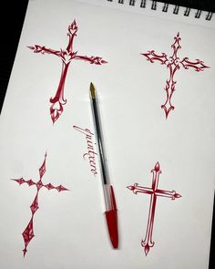 a pen sitting on top of a piece of paper next to some cross designs and writing