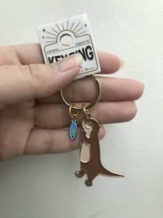 a person holding a keychain with a small animal on it's side