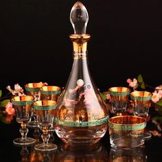 a glass decanter with gold rims and cups