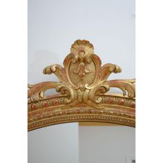 an ornate gold headboard with intricate carvings on the top and sides, against a white wall