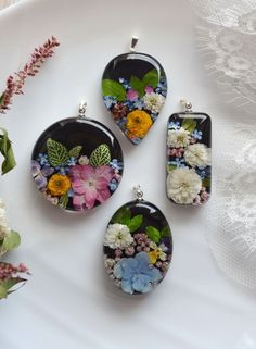 three pendants with flowers on them sitting on a table next to a flower bouquet