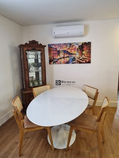 a white table and chairs in a room with wood floors, paintings on the wall