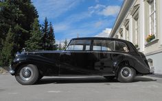 an old black car parked in front of a building