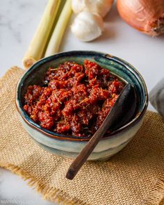 a bowl filled with chili next to some onions and celery on a table