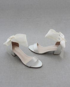 two pairs of white shoes with bows on the toes and heels are sitting next to each other