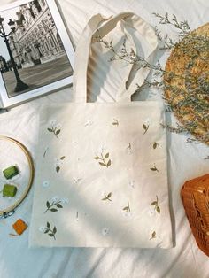 a white bag sitting on top of a bed next to a basket and some pictures