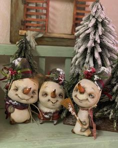 three small figurines sitting next to each other on a shelf in front of christmas trees