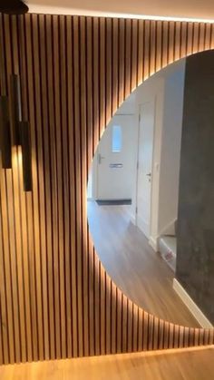 an oval mirror on the wall in front of a wooden paneled wall and floor