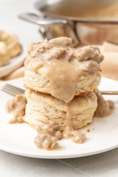 a stack of biscuits covered in gravy on top of a white plate