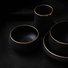 three black and gold dishes on a black surface, with one bowl in the middle