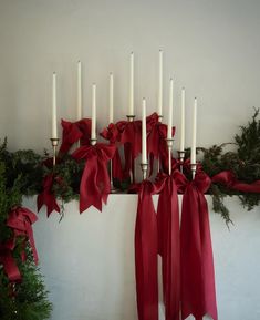 a bunch of candles that are next to some christmas wreaths with red bows on them