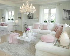 a living room filled with furniture and a chandelier hanging from the ceiling over a white rug