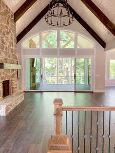 a large open living room with stone fireplace and wood flooring, surrounded by windows