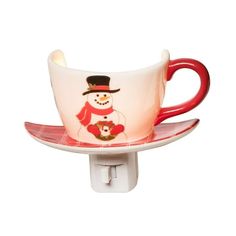 a red and white cup with a snowman on it is sitting on a plate