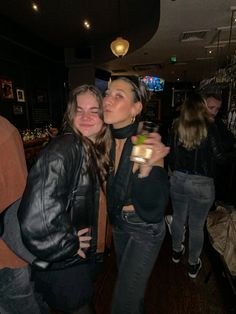 two women standing next to each other at a bar