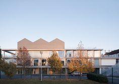 the building has many windows and balconies on it's sides, as well as several trees