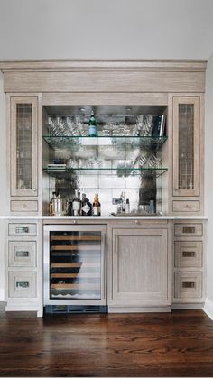 a kitchen with an open cabinet and wine glasses on the counter top, along with other items