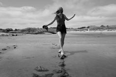 black and white photograph of woman running on beach