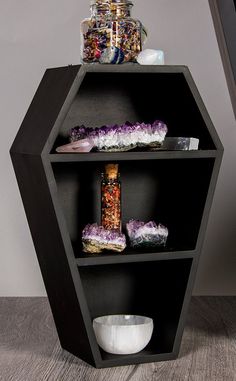 a black hexagonal shelf with three shelves filled with different types of candy and confections